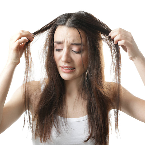 Ragazza che si tira i capelli a destra e sinistra. Capelli visivamente sporchi.